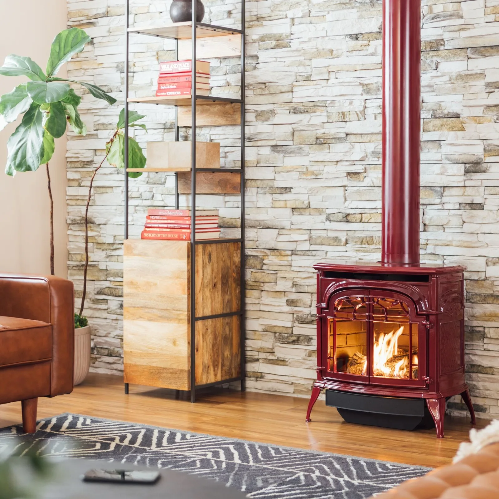 Red enamel gas stove against a stacked stone wall in a living room