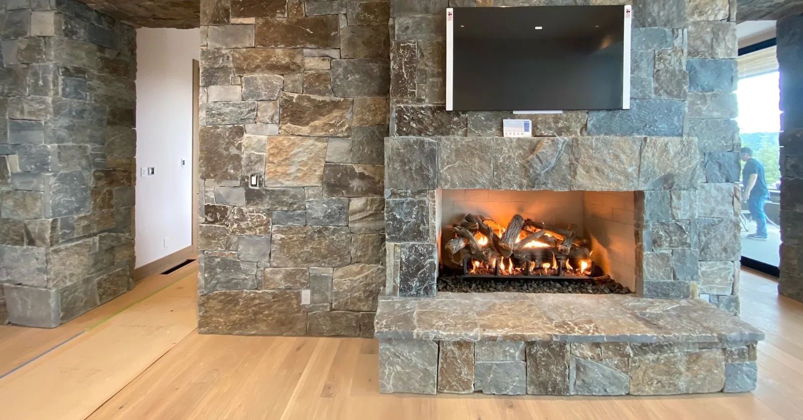 Stone masonry fireplace with a gas log set burning