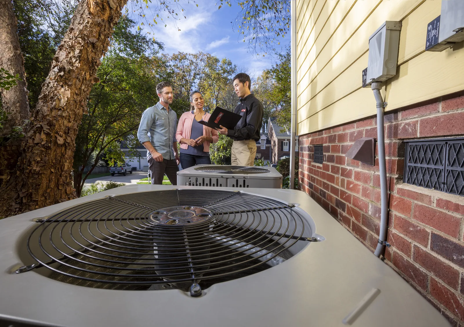 New Trane air conditioner condenser at a home, with the install team in the background