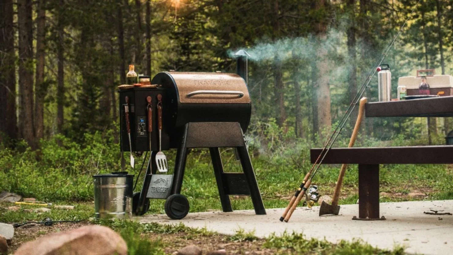 Traeger pellet grill smoking at a forest campsite