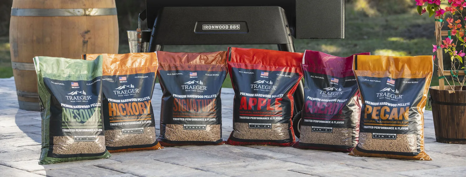Bags of Traeger hardwood pellets lined up in front of an Ironwood 885 pellet grill