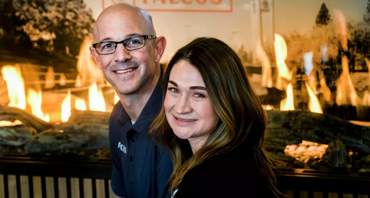 Grant and Andrea Falco in front of a fireplace display at Falco's